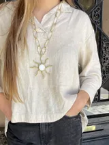 Collar dorado con cadena de eslabones grandes y dije de sol con centro de nácar blanco.