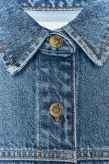 Cazadora de denim celeste de corte recto, con cuello solapa, manga larga, bolsillos delanteros de plastrón y cierre frontal con botones metálicos.