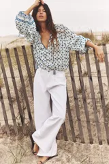 Pantalón de jean blanco, de tiro medio, corte wide leg y pinzas delanteras.