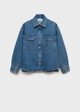 Campera de jean azul con corte recto, cuello camisero, cierre frontal con botones a presión, mangas largas con puños abotonados y dos bolsillos de parche con solapa en el pecho.