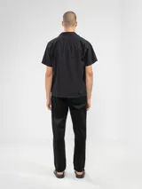 Camisa de manga corta color crema, con cuello camp y calce relajado. Confeccionada en una mezcla de lino y algodón, con botones de madera y parche característico de Polonio.