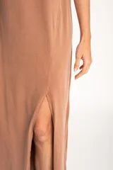 Vestido largo color visón de algodón con cuello redondo y mangas cortas. Presenta un tajo alto en el frente.