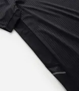 Remera deportiva de manga corta y cuello redondo, color beige claro, con textura acanalada vertical. Presenta detalles reflectantes en los hombros.