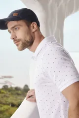 Remera tipo polo blanca estampada con mini print en todo el cuerpo, con botones personalizados y logo en el pecho.