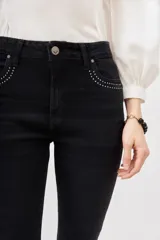 Pantalón de jean negro de corte flare con detalle de tachas metálicas en los bolsillos delanteros.