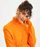 Blusa de punto color blanco, con cuello alto, manga larga y diseño liso.