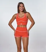 Conjunto deportivo naranja con costuras blancas, compuesto por un top con logo 'bk.' y un short de tiro alto.