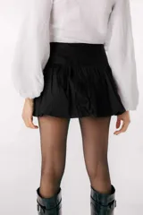 Minifalda negra con volados y detalle de etiqueta con logo en el lateral.