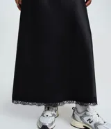 Pollera new midi negra de satén, con corte fluido y detalle de encaje en el ruedo.