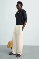 Pantalón de lino color crudo, de corte ancho, con cintura elástica ajustable con cordón, bolsillos laterales y trasero.