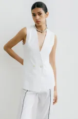 Chaleco sastrero color crema de lino, con cuello en V profundo y cierre cruzado con botón.