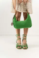 Cartera de hombro tejida a crochet color verde, con asa de cuero marrón y cierre.