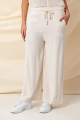 Pantalón ancho color beige, de hilo, con cintura elastizada ajustable con cordón y bolsillos laterales.