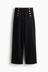 Pantalón negro de punto grueso, tiro alto con elástico oculto, botones dorados decorativos en el frente y piernas rectas de corte holgado.