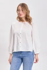 Blusa blanca de cuello redondo con cierre frontal de botones y mangas largas tipo balloon (abullonadas) con puños.