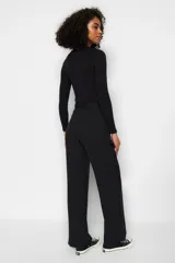 Pantalón palazzo negro de tiro alto con cinturón y corte holgado.