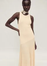 Vestido largo color durazno, de tejido de punto fino con diseño plisado y evasé. Sin mangas y con cuello halter.