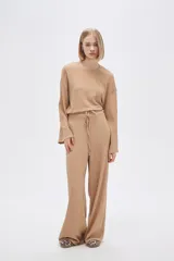 Pantalón de calce ancho y tiro alto, color beige con textura.