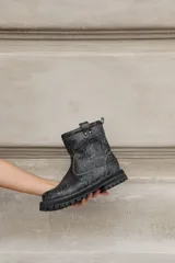 Botas cortas de cuero color gris gastado, con suela track y detalle de hebilla en la caña.