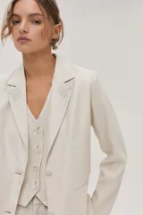 Blazer color crema de lino metalizado con bordado de hilo metálico en las solapas delanteras.