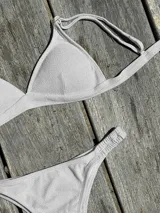 Conjunto de bikini turquesa con corpiño triangular de corte fijo, breteles regulables y almohadillas desmontables, y bombacha vedetina con frunce elástico en los costados.