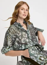 Camisa de manga larga con estampado animal print en tonos verde, marrón y blanco. Tiene cuello clásico, cierre frontal con botones y puños con tres botones.