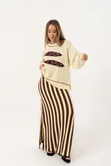 Sweater color manteca de tejido de punto con cuello redondo y ribete marrón. Presenta dos peces marrones tejidos en el frente con detalles bordados a mano.