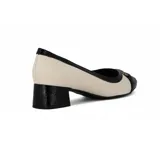 Zapato de tacón bajo Comfortflex, color blanco y negro charol, con punta redonda y detalle de moño metálico.