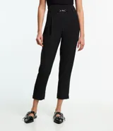 Pantalón negro de corte carrot, con trabillas en la cintura, detalle metálico y pliegues.