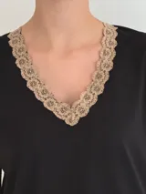 Conjunto de pijama de dos piezas color negro, compuesto por una remera de manga corta con escote en V adornado con puntilla beige, y un short con lazo frontal beige y terminación de puntilla beige en el ruedo.