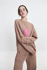 Buzo de felpa color marrón con estampa frontal en rosa, cuello redondo y hombros caídos.