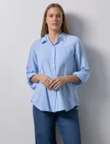 Camisa celeste de lino, con cuello con solapa, escote en V y abertura central con botones. Largo de manga regulable con presilla y botón. Delantera con bolsillo aplicado.