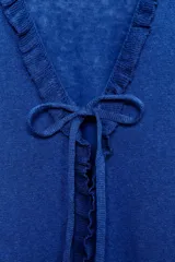 Chaqueta azul de punto con manga larga, volantes en el escote y en los puños, y cierre frontal con lazada.