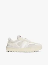 Zapatillas Tommy Jeans de estilo running, color blanco hueso, con exterior de ante, interior de poliéster y suela gruesa de goma con tacos. Presentan paneles con mezcla de texturas y detalles distintivos de la marca.