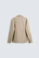 Sobrecamisa negra de tejido con elasticidad, cuello solapa, manga larga con puño abotonado, bolsillos de plastrón en el pecho y cierre frontal con botones a presión.