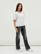 Remera negra de corte holgado con cuello en V y apliques de tachas doradas en los hombros.