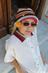 Gorro tipo bucket tejido al crochet con rayas horizontales en colores celeste, marrón, naranja y rojo.