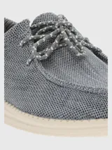 Alpargata negra con cordones elásticos y suela blanca con textura.