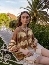 Campera tejida marrón y beige con diseño de ondas, cierre frontal y mangas largas abullonadas.