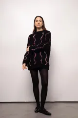 Sweater negro tejido a mano con lana merino, con diseño de ochos en blanco y rojo.