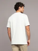 Remera blanca de manga corta con cuello redondo y logo de Calvin Klein en un recuadro rojo.