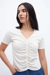 Remera color crudo con escote en V, cartera de botones y frunces.