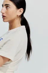 Remera color crudo de algodón con cuello redondo y mangas cortas. Estampado frontal con la frase "LES MERS" y dibujos de conchas y estrellas de mar en color azul.