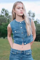 Top cropped de denim celeste, de corte ajustado, con cuello redondo, cierre de botones y solapas de bolsillo decorativas con botón en el pecho. Tiene pinzas adelante y atrás para crear un efecto "cintura de avispa".