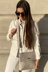 Bandolera color gris con correa extensible con tachas y arandelas. En el interior tiene forro y bolsillo interno con cierre. La solapa tiene un imán para cerrar con mayor seguridad.