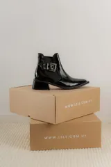 Botines Chelsea color beige con elásticos laterales negros, punta cuadrada, detalle de hebilla lateral y tacón bloque bajo.