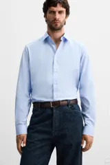 Camisa celeste de corte slim fit, confeccionada en tejido de algodón. Tiene cuello italiano, mangas largas con puños abotonados y cierre frontal con botones.