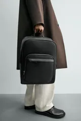 Mochila negra con acabado grabado, compartimento principal con cierre de cremallera, espacio interior para dispositivos electrónicos de hasta 13 pulgadas y bolsillo con cierre de cremallera. Dos bolsillos frontales con cierre de cremallera, parte posterior acolchada con bolsillo con cierre de cremallera y banda de sujeción para equipaje. Asa de mano y dos asas de hombro ajustables y acolchadas.