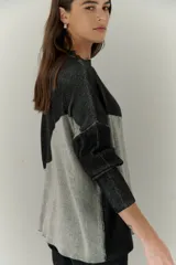 Buzo de punto con diseño geométrico en bloques de color gris y negro, de cuello redondo y mangas largas.