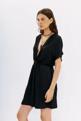 Vestido corto color negro con escote cruzado y mangas cortas, de calce relajado y cintura elastizada.